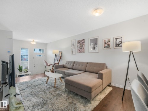 Expansive living area featuring wood-finish flooring, light wall tones, and recessed ceiling lighting - #21 1140 Chappelle Bv Sw, Edmonton, AB - Indoor Photo Showing Living Room