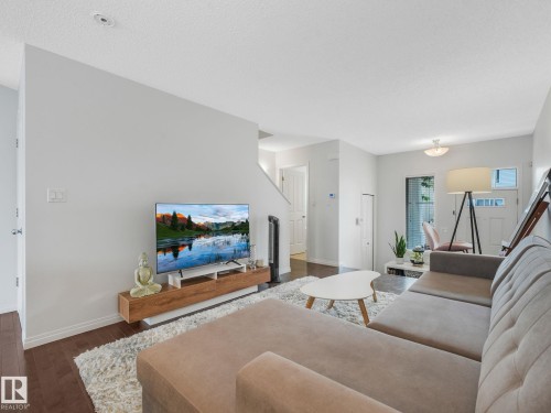 Living area with dark wood-finish flooring, light-toned walls, and a floating media console - #21 1140 Chappelle Bv Sw, Edmonton, AB - Indoor Photo Showing Living Room
