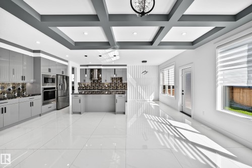 White tile flooring, coffered ceiling, modern kitchen cabinetry, integrated stainless steel appliances, and a kitchen island - 3101 Soleil Boulevard, Beaumont, AB - Indoor