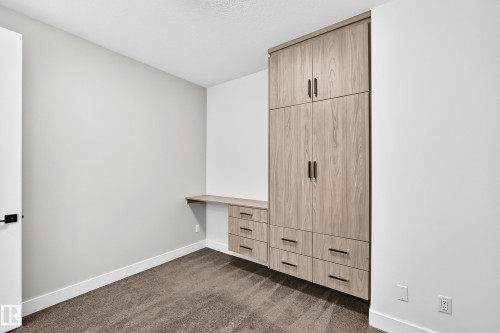 Built-in cabinetry with wood-finish doors and drawers, integrated desk space, and dark hardware - 3101 Soleil Boulevard, Beaumont, AB - Indoor Photo Showing Other Room