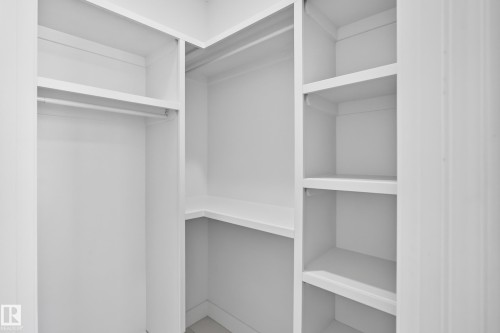 Built-in closet system featuring white shelving and hanging rods - 3101 Soleil Boulevard, Beaumont, AB - Indoor With Storage