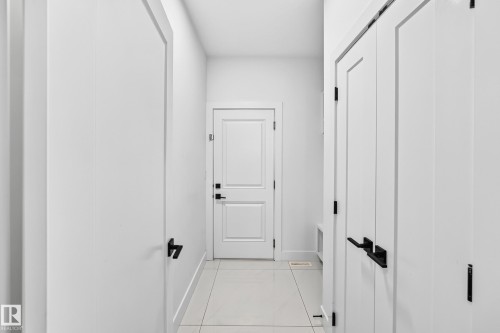 White paneled doors with matte black hardware, light-colored tile flooring, and white painted walls - 3101 Soleil Boulevard, Beaumont, AB - Indoor Photo Showing Other Room