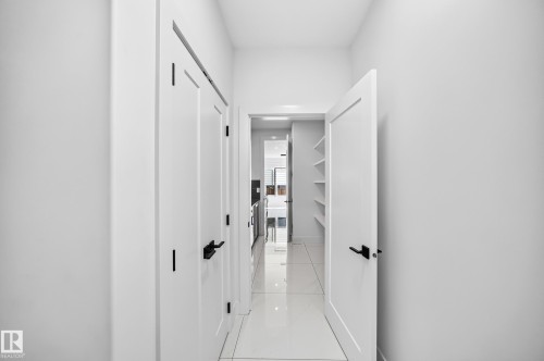 Hallway with white walls, white doors, black hardware, and tiled flooring - 3101 Soleil Boulevard, Beaumont, AB - Indoor Photo Showing Other Room