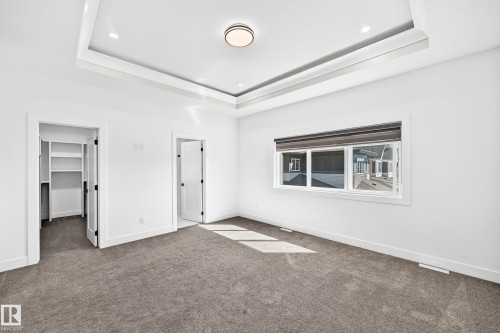 Tray ceiling with recessed lighting, central flush mount light fixture, gray carpet flooring, and a white-framed window - 3101 Soleil Boulevard, Beaumont, AB - Indoor Photo Showing Other Room
