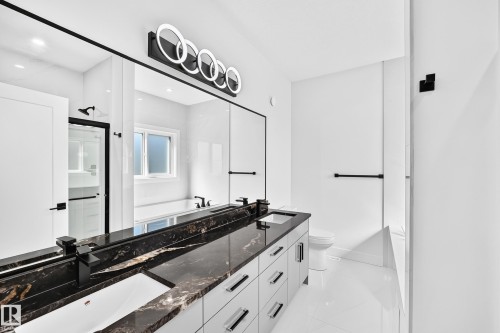 Dual vanity with dark stone countertop, undermount sinks, and matte black fixtures - 3101 Soleil Boulevard, Beaumont, AB - Indoor