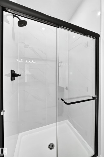 Corner shower enclosure with matte black hardware, clear glass sliding door, integrated shower head, and white tile surround - 3101 Soleil Boulevard, Beaumont, AB - Indoor Photo Showing Bathroom