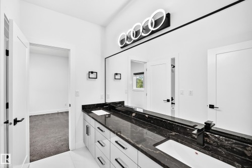Dual vanity with a dark polished countertop, undermount sinks, and matte black fixtures - 3101 Soleil Boulevard, Beaumont, AB - Indoor