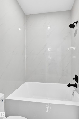 White tiled shower and tub combination featuring a matte black shower head and faucet - 3101 Soleil Boulevard, Beaumont, AB - Indoor Photo Showing Bathroom