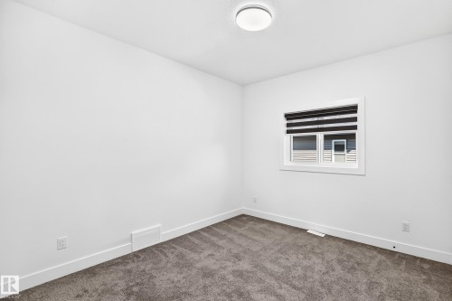 White walls with dark gray carpet, featuring a window with blinds and a flush mount ceiling light - 3101 Soleil Boulevard, Beaumont, AB - Indoor Photo Showing Other Room