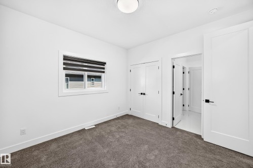 White walls, recessed window, dark gray carpet, white double-door closet, and a white door with black hardware - 3101 Soleil Boulevard, Beaumont, AB - Indoor Photo Showing Other Room