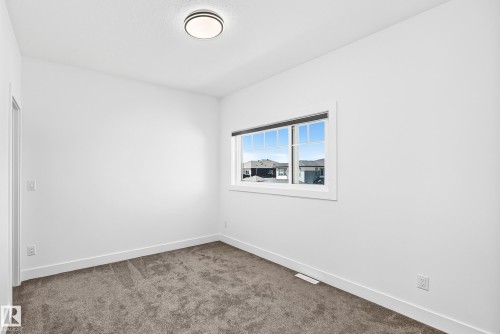 Neutral interior walls, carpet flooring, a rectangular window with white trim, a flush mount ceiling light fixture, and white baseboards - 3101 Soleil Boulevard, Beaumont, AB - Indoor Photo Showing Other Room