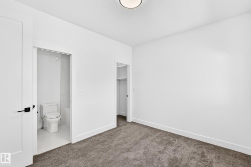 Neutral wall paint, flush mount ceiling light, carpeted flooring, built-in closet, and a white toilet - 3101 Soleil Boulevard, Beaumont, AB - Indoor Photo Showing Other Room
