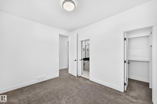 Plush carpet flooring, integrated ceiling light fixture, white interior doors, walk-in closet with built-in shelving, and a vanity with a mirror and lighting - 3101 Soleil Boulevard, Beaumont, AB - Indoor Photo Showing Other Room