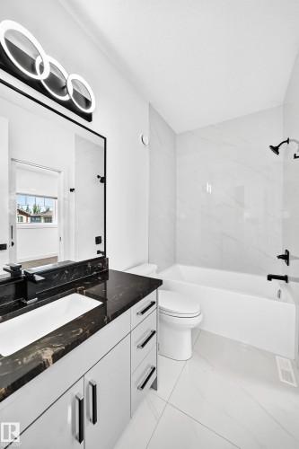 White vanity with black-veined countertop, integrated sink, and matte black faucet - 3101 Soleil Boulevard, Beaumont, AB - Indoor Photo Showing Bathroom