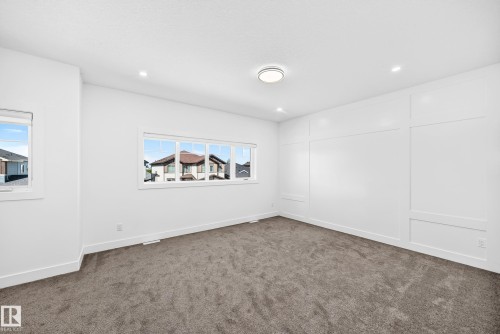 Broadloom carpeting, recessed ceiling lighting, a contemporary ceiling fixture, a multi-pane window, and decorative wall paneling - 3101 Soleil Boulevard, Beaumont, AB - Indoor