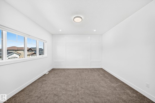 Neutral-toned carpeting, decorative wall paneling, and an overhead flush-mount light fixture - 3101 Soleil Boulevard, Beaumont, AB - Indoor Photo Showing Other Room