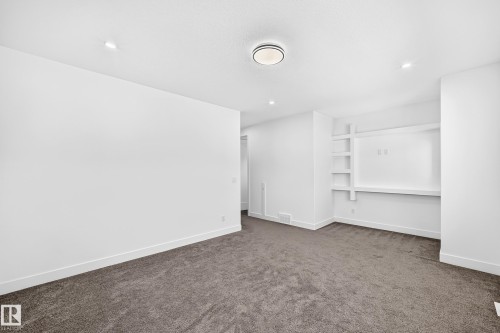 Recessed lighting, flush-mount ceiling light, built-in shelving, built-in media console, and neutral carpeting - 3101 Soleil Boulevard, Beaumont, AB - Indoor Photo Showing Other Room