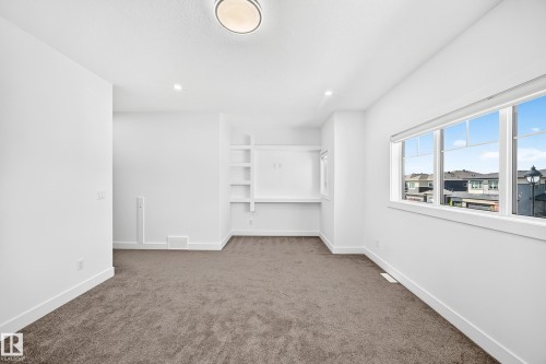 Recessed lighting, large window with white trim, built-in shelving, built-in desk, and grey carpet flooring - 3101 Soleil Boulevard, Beaumont, AB - Indoor Photo Showing Other Room