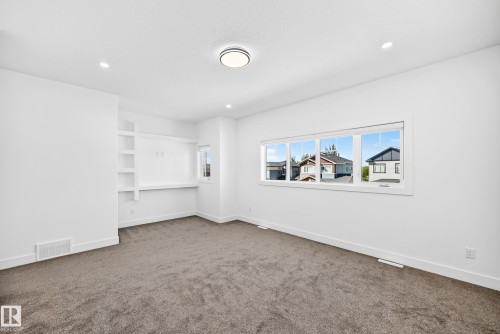 Recessed lighting, large window with roller shades, built-in desk, built-in shelving, and neutral carpeting - 3101 Soleil Boulevard, Beaumont, AB - Indoor Photo Showing Other Room