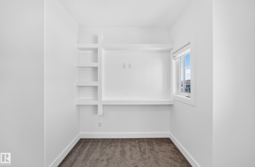 Built-in shelving and desk unit, white trim, window with natural light, and carpeted flooring - 3101 Soleil Boulevard, Beaumont, AB - Indoor With Storage