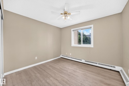 Wood-finish flooring, neutral-toned walls, and a ceiling fan with integrated lighting - #204 11218 80 St Nw, Edmonton, AB - Indoor Photo Showing Other Room