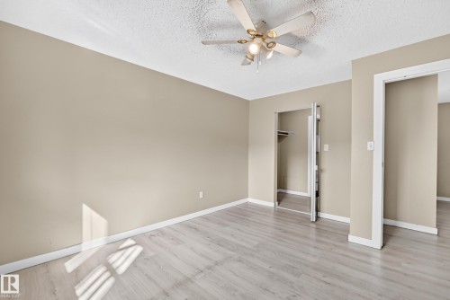Neutral-toned walls, wood-finish flooring, ceiling fan with integrated lighting, bi-fold closet doors, and a secondary doorway - #204 11218 80 St Nw, Edmonton, AB - Indoor Photo Showing Other Room