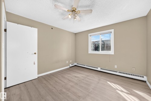 Wood-finish flooring, neutral wall tones, ceiling fan, and baseboard heat - #204 11218 80 St Nw, Edmonton, AB - Indoor Photo Showing Other Room