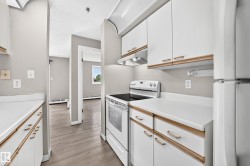Galley kitchen with white cabinetry and wood-finish trim, white solid surface countertops, and a white electric range - 