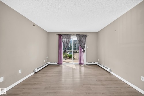 Wood-finish flooring, neutral wall tones, and a sliding glass door - #204 11218 80 St Nw, Edmonton, AB - Indoor Photo Showing Other Room