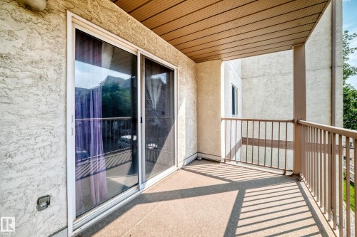 Private balcony featuring a stucco exterior, sliding glass door, and metal railings - #204 11218 80 St Nw, Edmonton, AB - Outdoor With Balcony With Exterior