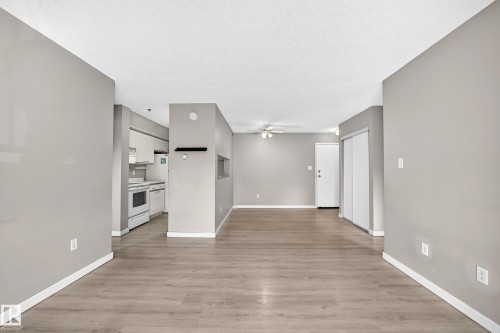 Expansive interior with wood-finish flooring, light grey walls, and white trim throughout - #204 11218 80 St Nw, Edmonton, AB - Indoor Photo Showing Other Room