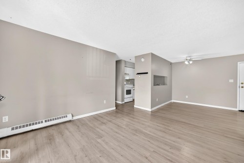 Wood-finish flooring throughout, light neutral wall paint, and a ceiling fan with integrated lighting - #204 11218 80 St Nw, Edmonton, AB - Indoor Photo Showing Other Room