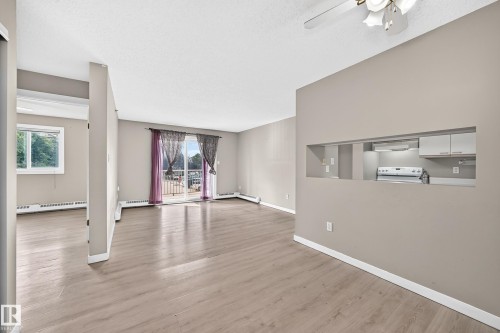 Wood-finish flooring, neutral wall paint, and a sliding glass door - #204 11218 80 St Nw, Edmonton, AB - Indoor Photo Showing Other Room