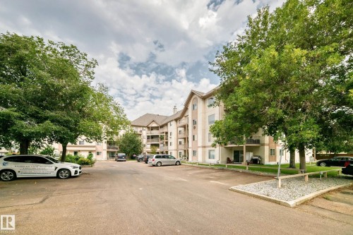 Multi-story building with a stucco exterior, multiple balconies, and a paved parking area - #204 11218 80 St Nw, Edmonton, AB - Outdoor With Facade