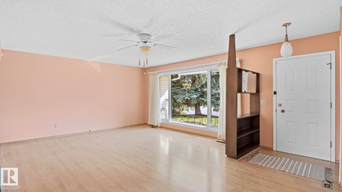 Spacious room featuring wood-finish flooring, a large picture window, and a ceiling fan - 8408 176 Street Nw, Edmonton, AB - Indoor Photo Showing Other Room