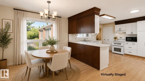 Wood-finish flooring, white upper cabinetry, dark wood-finish lower cabinetry, white appliances, and a window with a chandelier - 8408 176 Street Nw, Edmonton, AB - Indoor