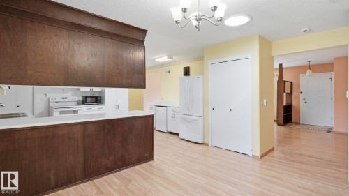Wood-finish flooring throughout, kitchen with wood-finish cabinetry, white countertops, and white appliances - 8408 176 Street Nw, Edmonton, AB - Indoor Photo Showing Kitchen