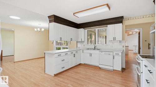 Kitchen featuring white cabinetry, light countertops, and wood-finish flooring - 8408 176 Street Nw, Edmonton, AB - Indoor Photo Showing Kitchen With Double Sink
