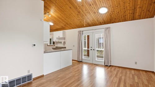 Vaulted wood-finish ceiling with a circular skylight, wood-finish flooring, white walls, and French patio doors - 8408 176 Street Nw, Edmonton, AB - Indoor Photo Showing Kitchen