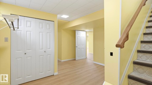 Wood-finish flooring, paneled white doors, square ceiling lighting, and a wood handrail - 8408 176 Street Nw, Edmonton, AB - Indoor Photo Showing Other Room
