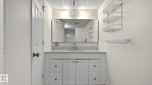 White vanity with integrated sink, chrome faucet, wall-mounted mirror, and overhead lighting - 8408 176 Street Nw, Edmonton, AB - Indoor Photo Showing Bathroom