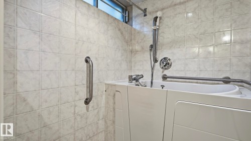 Walk-in bathtub with chrome fixtures, tiled walls, and grab bars - 8408 176 Street Nw, Edmonton, AB - Indoor Photo Showing Bathroom
