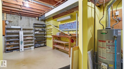Basement area featuring a water heater, exposed wood joists, concrete walls, and utility shelving - 8408 176 Street Nw, Edmonton, AB - Indoor Photo Showing Basement