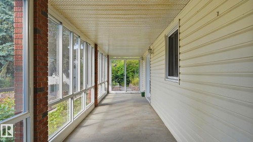 Enclosed sunroom featuring a concrete floor, brick column accents, and a paneled ceiling - 8408 176 Street Nw, Edmonton, AB - Outdoor With Exterior
