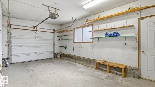 Attached garage featuring a concrete floor, automatic garage door opener, and integrated shelving - 8408 176 Street Nw, Edmonton, AB - Indoor Photo Showing Garage