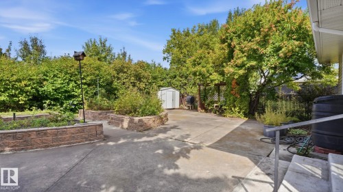 Concrete patio with raised garden beds featuring stacked stone retaining walls - 8408 176 Street Nw, Edmonton, AB - Outdoor