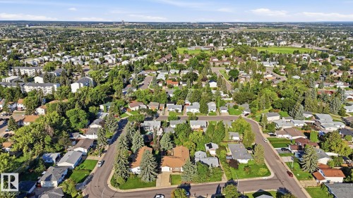 Aerial perspective showcasing a residential neighborhood with mature trees, established streets, and a mix of single-family homes and multi-unit buildings - 8408 176 Street Nw, Edmonton, AB - Outdoor With View