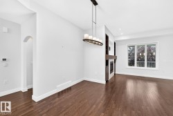 Hardwood-style flooring throughout, featuring a contemporary linear chandelier, an arched doorway, and a built-in fireplace with shelving - 
