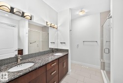 Dual vanity with granite countertops, integrated sinks, a mosaic tile backsplash, and dark wood cabinetry - 