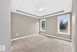 Tray ceiling with crown molding, two windows with white trim, light gray carpet, and a flush-mount ceiling light fixture - 